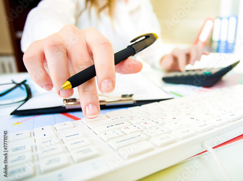 Woman with beautiful hands working on the calculator and keyboar photo