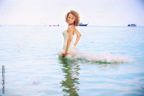 blonde bride stand in seawater