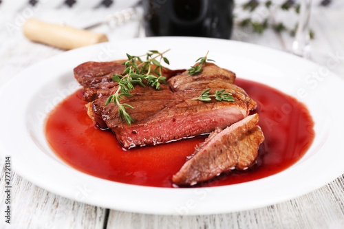 Steak with wine sauce on plate on wooden table