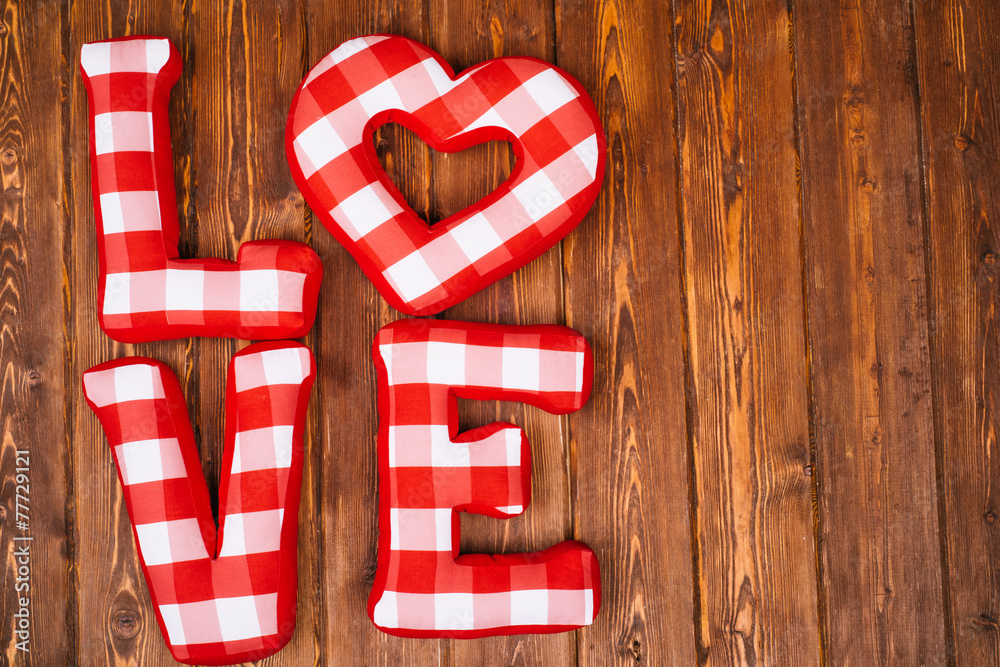 Love word of plush red letters on wood background. Full plaid