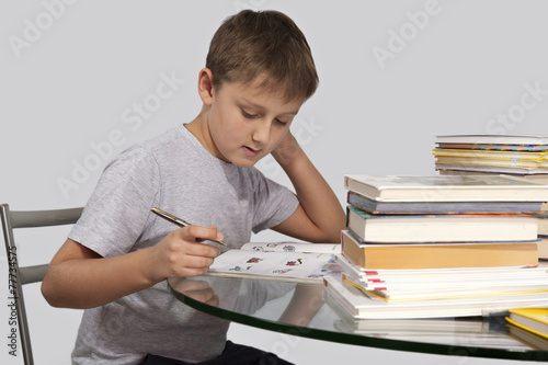 Мальчик делает уроки с ручкой в руке в полоборота
