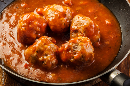 Meatballs with tomato sauce on black pan