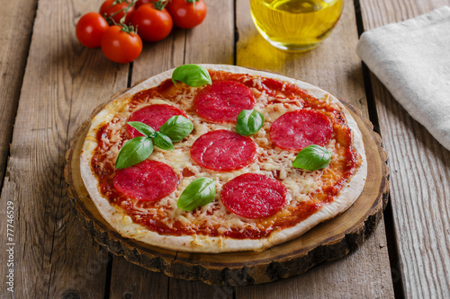 pizza with salami round on a wooden surface