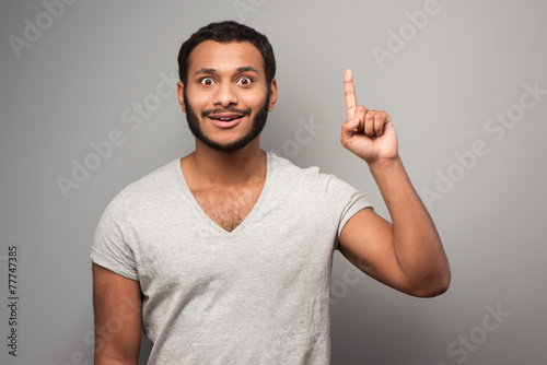 Tableau sur toile Cheerful mixed race man pointing up