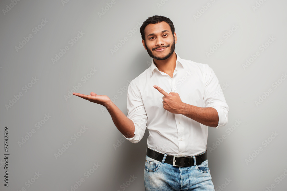 © Friends Stock - Mixed race man pointing aside on grey background © Friends Stock - Mixed race man pointing aside on grey background