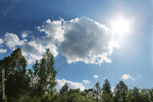 A bright summer sun in the blue sky with clouds © lenoraa