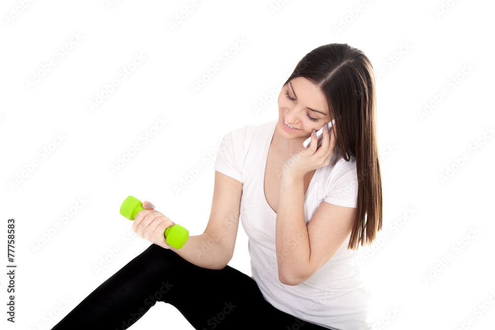Smiling girl talking on phone and lifting dumbbells Smiling girl talking on phone and lifting dumbbells