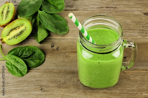 Healthy green smoothie with spinach and kiwi in a jar on wood