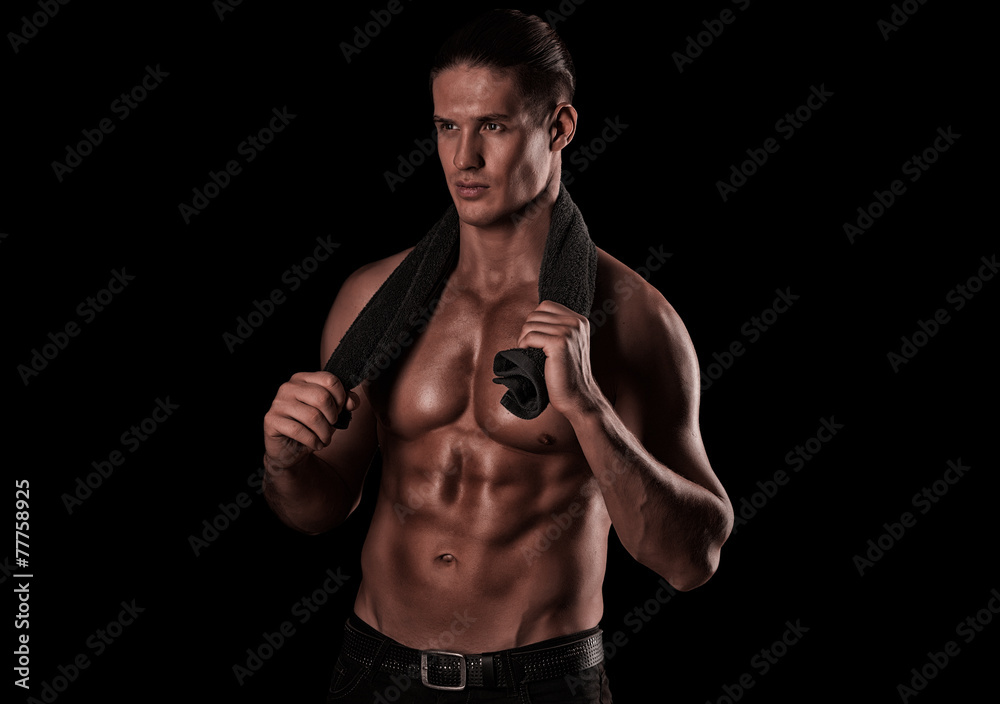 Healthy muscular young man after a workout on dark background