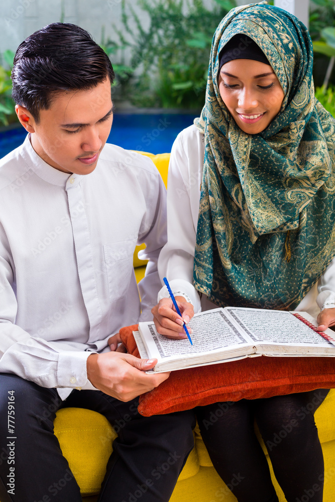 Asian Muslim couple reading together Koran or Quran
