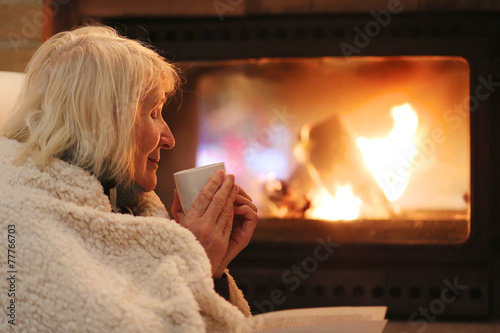 Senior woman relaxing at by fireplace