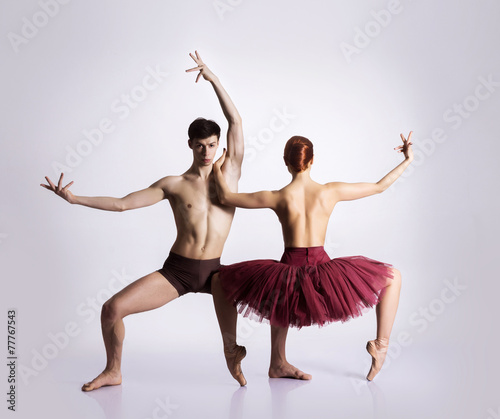Couple of young and athletic ballet dancers on grey