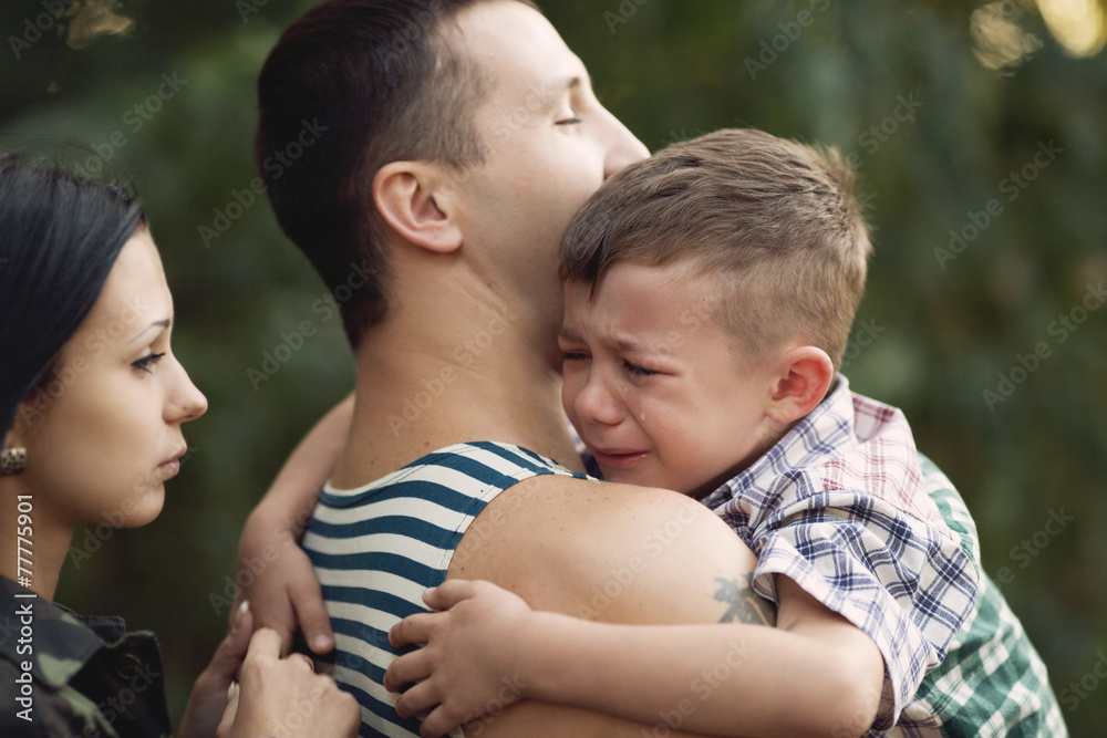 Family and soldier in a military uniform say goodbye before a separation Family and soldier in a military uniform say goodbye before a separation