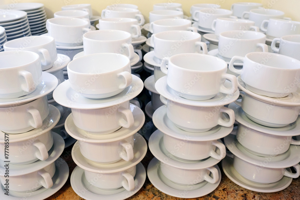 White cups for tea piled on table with plates for coffee break White cups for tea piled on table with plates for coffee break