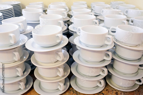 White cups for tea piled on table with plates for coffee break