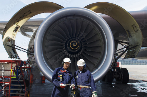 airplane mechanics in front of jumbo jet engine