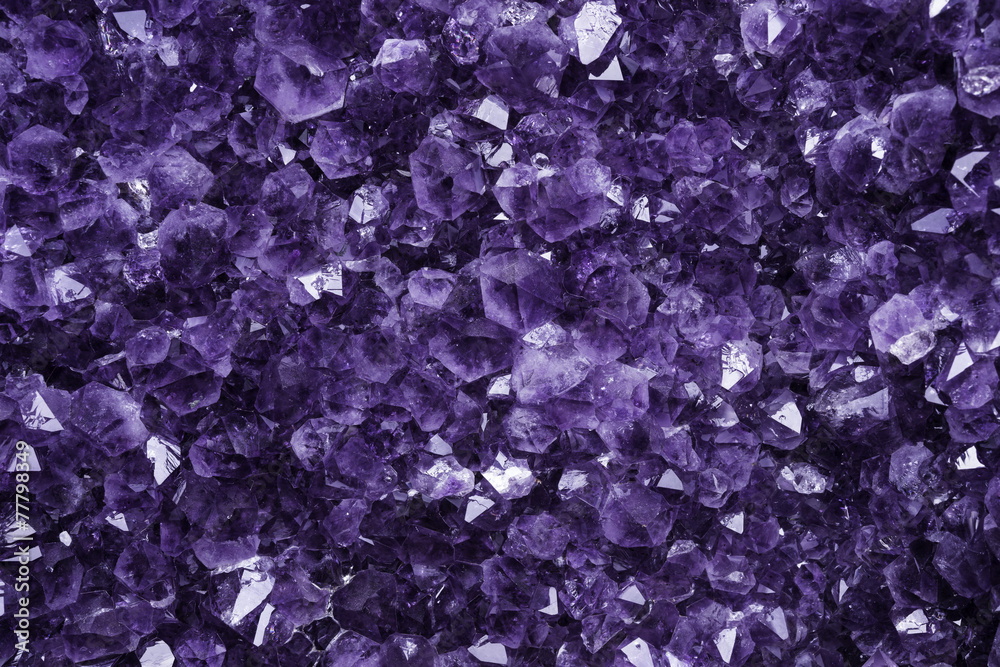 Naklejka premium Dettaglio dei cristalli viola di un ametista gigante con qualche riflesso e luce piatta.