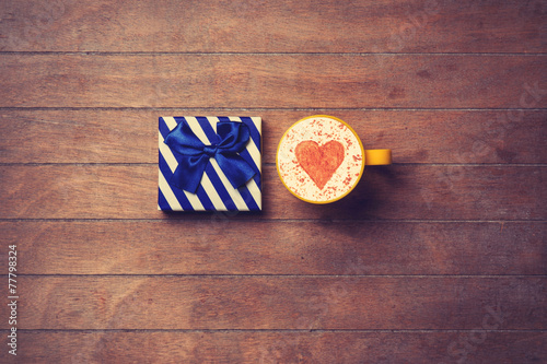 Cup and gift box on wooden background