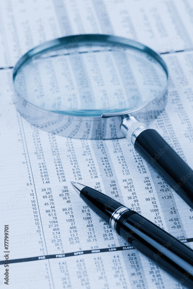 Pen and magnifier rest on stock price detail financial newspaper Pen and magnifier rest on stock price detail financial newspaper