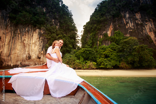 groom embrace bride sitting on longtail boat © SlavaStock