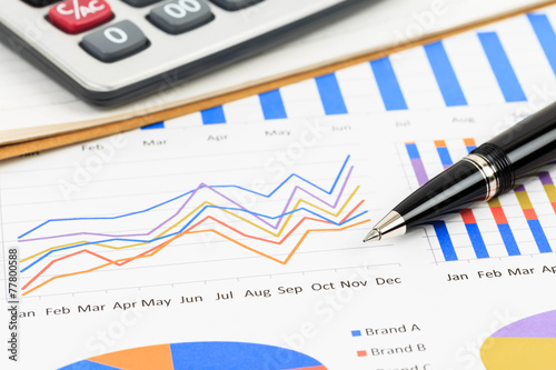 Marketing report chart and graph analysis with pen and calculato photo