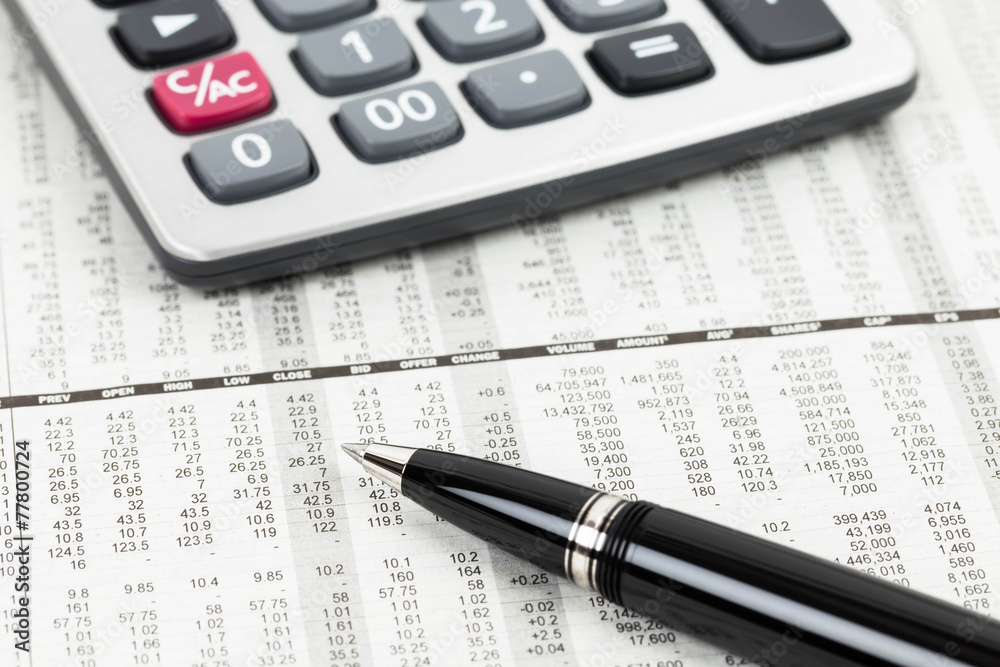 Pen and calculator on stock price detail financial newspaper Pen and calculator on stock price detail financial newspaper