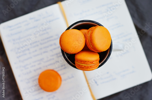 Orange macaroon upon open diary with notes