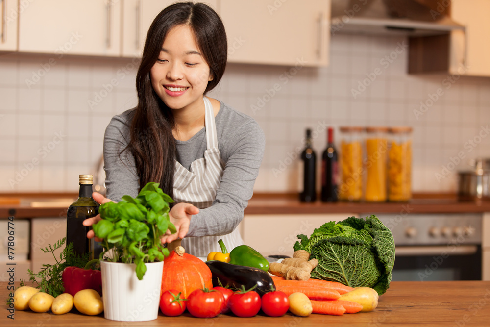 asian smiling woman standing in the kitchen with colorful ingred