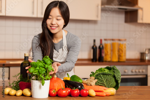 asian smiling woman standing in the kitchen with colorful ingred