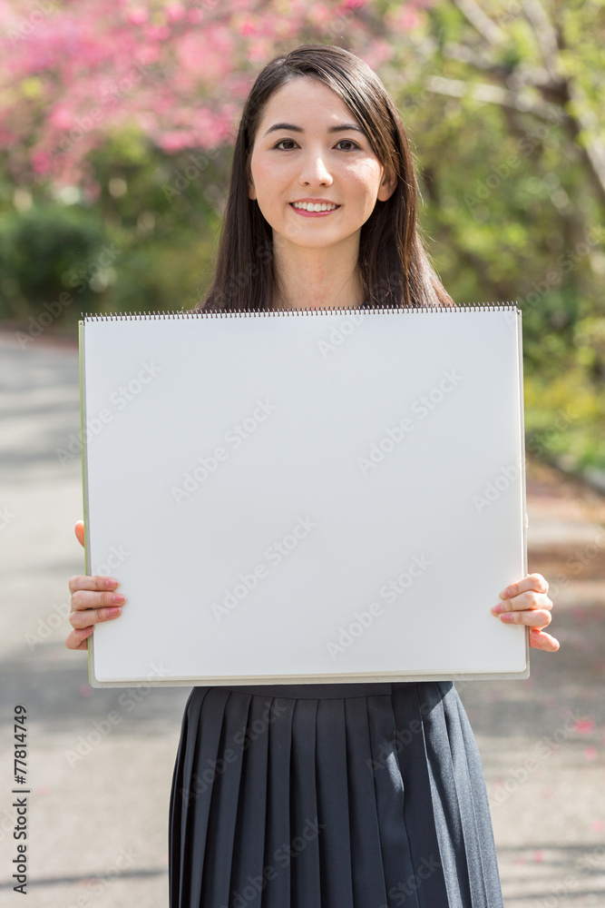 桜をバックにホワイトボードを持つ女子学生 桜をバックにホワイトボードを持つ女子学生