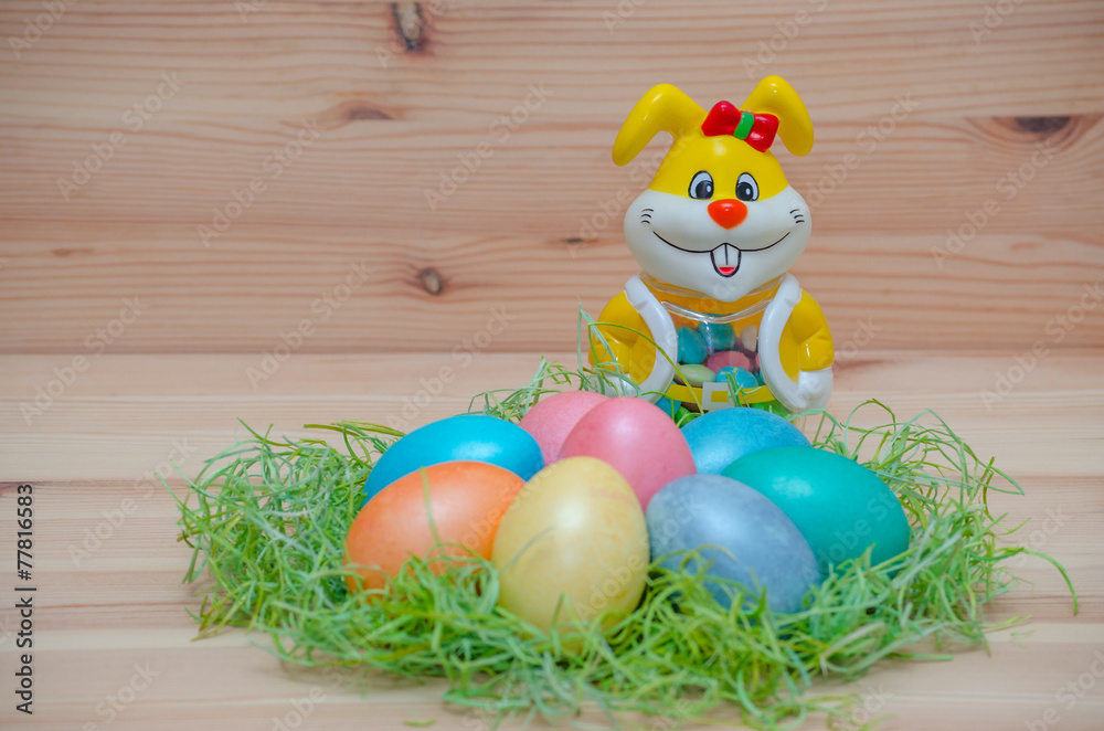 happy bunny with easter eggs in a nest on the wooden background