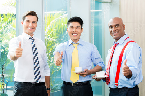 Three businessmen showing the thumbs up