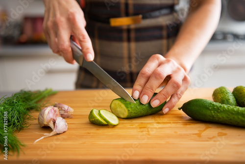 Closeup on young housewife cutting cucumber for pickling