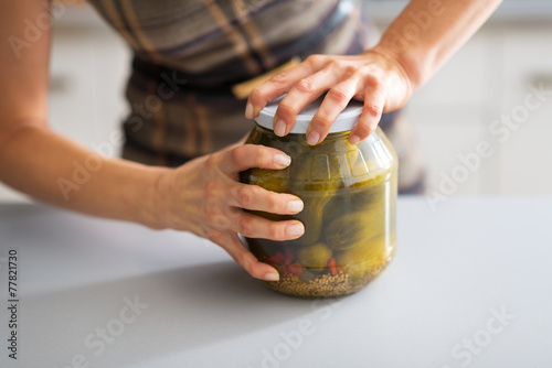 Closeup on young housewife opening jar of pickled cucumbers photo