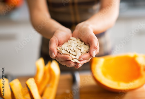 Closeup on young housewife showing pumpkin seeds photo