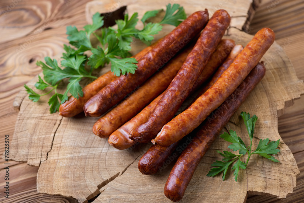 Stack of smoked sausages with parsley over wooden background