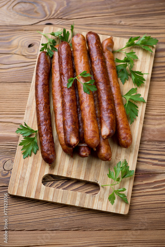 Wooden cutting board with sausages and parsley, high angle view