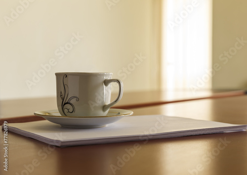 Cup and a stack of papers on his desk