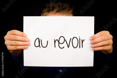 Child holding sign with French word Au Revoir - Goodbye