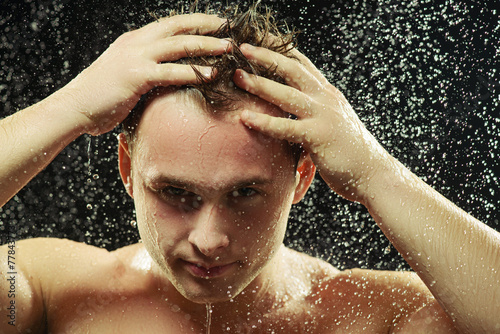 Handsome young man taking a shower