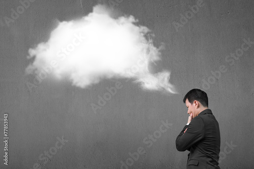 Businessman thinking about white cloud thought bubble with concr
