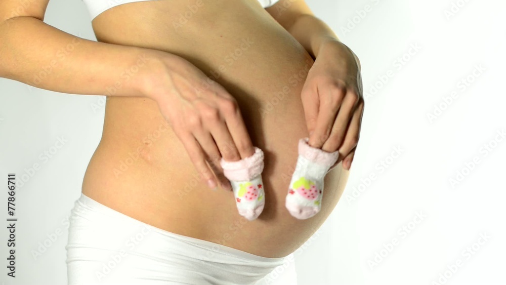 pregnant woman holding baby socks on her belly pregnant woman holding baby socks on her belly