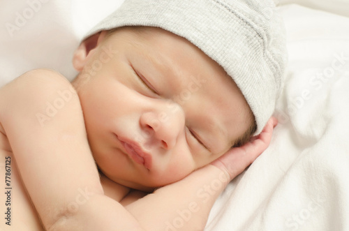 New born baby boy with cute gray hat sleeping taking a nap.