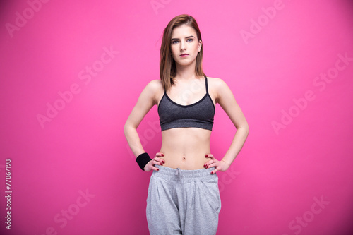 Beautiful sports woman standing over pink background photo