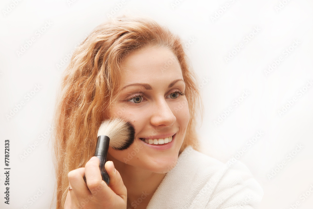 Attractive woman doing make-up on face.