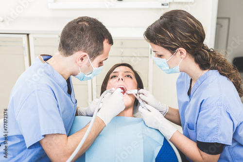 Dentist and Dental Assistant examining Patient teeth.