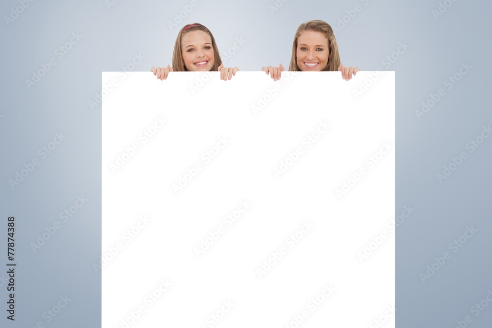 Composite image of close up of young women behind a blank sign