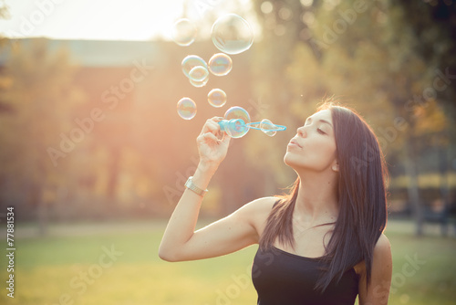 young beautiful brunette straight hair woman blowing soap bubble