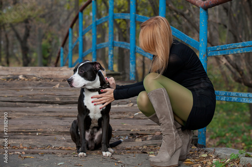 Long-haired blonde woman in high boots stroking dog