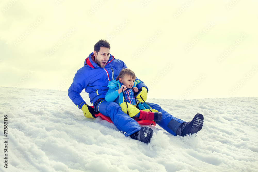little boy and his father sledding very fast,